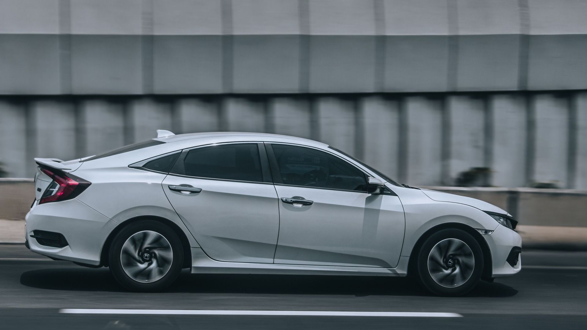 A sleek white car speeding down an urban road, illustrating motion and style.